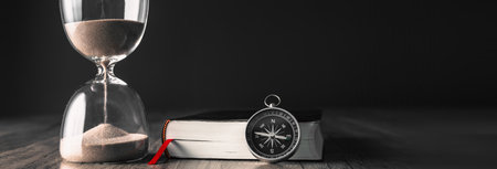 On the table is a book, a compass and an hourglassの写真素材