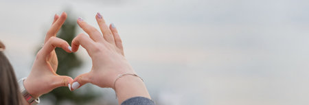 Woman showing a heart on the background of the skyの写真素材