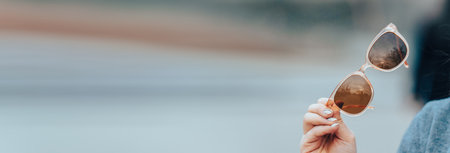 Woman holding sunglasses in her handの写真素材