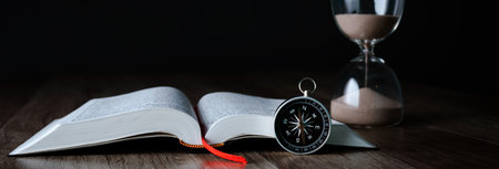On the table is a book, a compass and an hourglass