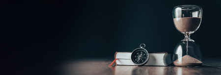 On the table is a book, a compass and an hourglassの写真素材