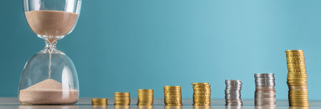 Coins and hourglass on wooden table