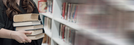 Girl stands with a bunch of books in her hand in the library