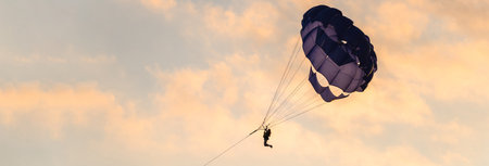 Skydiver falls into the sea at sunsetの写真素材