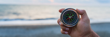 Holds a compass against the background of the sea in the eveningの写真素材