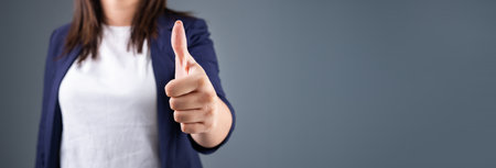 Woman showing thumbs up on gray backgroundの写真素材