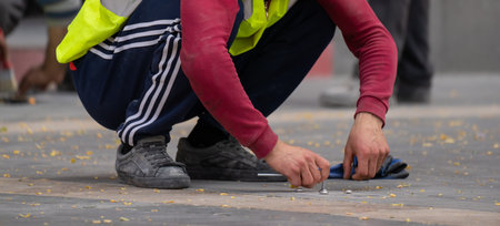 A municipal worker in uniform renews the road linesの写真素材