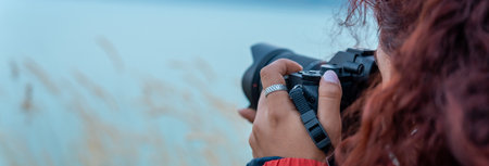 Woman holding a camera by the lake in the evening