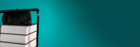 Student hat on books on blue backgroundの写真素材
