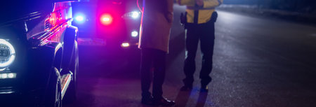 police officer stands next to a car he pulled over for speeding, reaching for the driver's ID, stock photoの写真素材