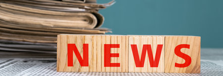 Newspapers and wooden cubes with the word "news" on a blue background stock photoの写真素材