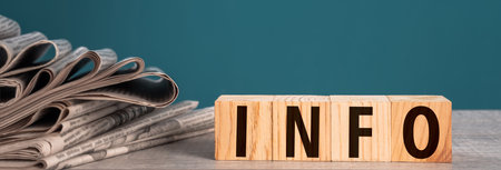 Newspapers and wooden cubes with "INFO" written on them, studio background, stock photoの写真素材