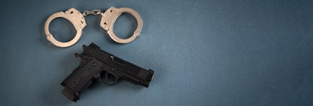 Gun and handcuffs on blue background, stock photo, criminal concept