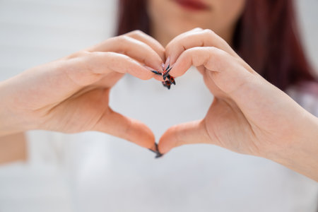 The girl makes a heart sign with her handsの写真素材