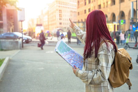 A girl tourist with a map in her hand, orienting herself in the city