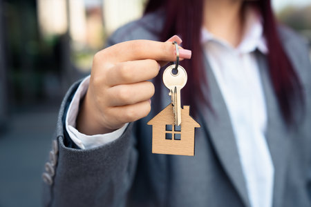 businesswoman holding small wooden house and key, house sale, business conceptの写真素材