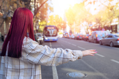 At the city bus stop, the girl tries to stop the bus and the car with her handの写真素材