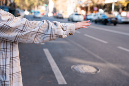 At the city bus stop, the girl tries to stop the bus and the car with her handの写真素材