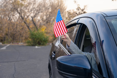 Driver waves US flag from inside carの写真素材