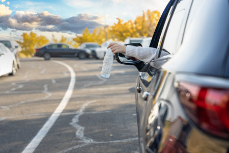 Girl throws plastic bottle out of car, ecological conceptの写真素材