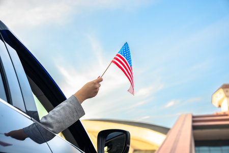 Driver waves US flag from inside carの写真素材