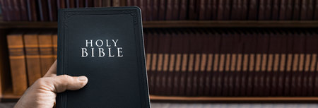 Holy Bible in human hand in library, Christian concept, religious symbolの写真素材