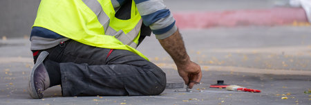 A municipal worker in uniform renews the road lines