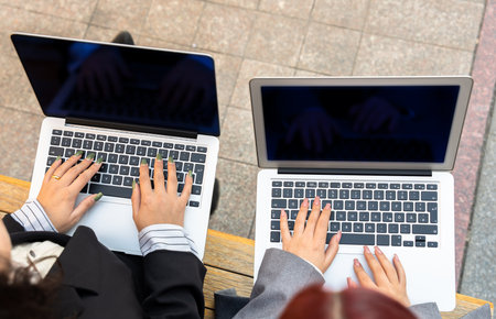 Businesswomen, partners working on laptops in the parkの写真素材
