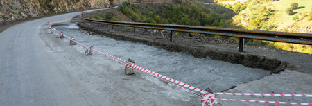 Damaged asphalt road, red tape for road construction work