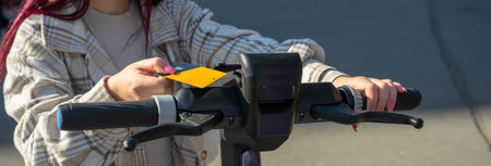 Young girl using a moped, paying with a card