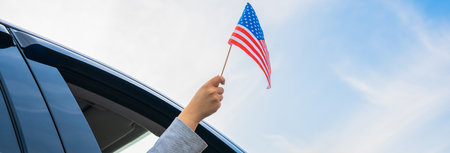 Driver waves US flag from inside carの写真素材