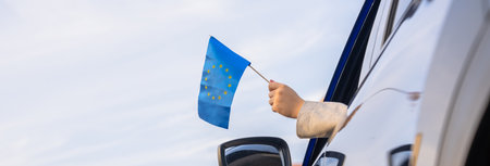 The driver waves the European Union flag from inside the car.