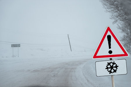 Road Sign Warning of Slippery Conditions Due to Snow and Ice for Safe Winter Driving.の写真素材