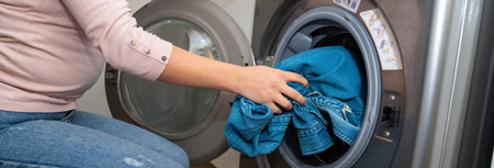 Housewife using a washing machine, loading clothes into the machineの写真素材