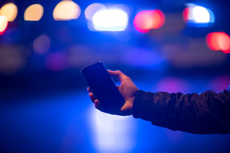 man holding phone with police in streetの写真素材