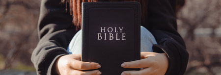 Girl sitting on train tracks holding Bible, spiritual concept