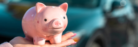 Pig piggy bank in woman's hand, car in background, saving to buy a carの写真素材