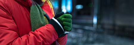 Young Man Shivering at a Bus Stop While Waiting for Public Transport in Cold Weather.の写真素材