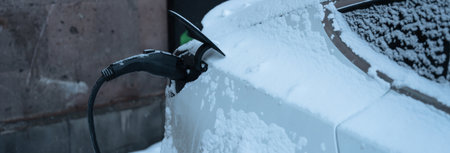 Electric Car Charging in Winter with Snow and Cold Weather Conditions.