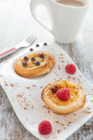 Cream cake and puff pastry with raspberries and chocolate. Cup of coffe and fork.
