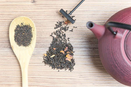 Teapot, black tea and wooden spoon on wooden background.の写真素材
