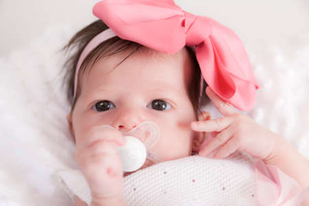 Baby with pacifier and pink tie.