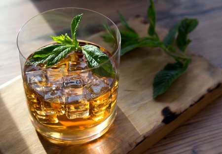 Ron glass with ice and mint on a wooden table background.