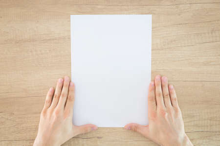 Man holding brochure with blank cover on wooden background. Table. Mock up for design.の写真素材