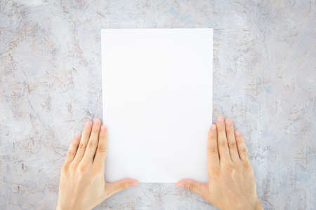 Man holding blank booklet with cover on worn white background. Mockup for the design.