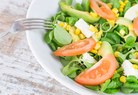 Organic salad leaves: arugula, watercress, lettuce, corn and tomato in a bowl. Close up. Fork supported. Healthy food concept.の写真素材