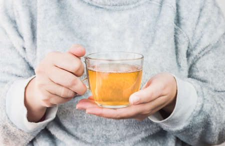Tea mug in female hands. Woman drinking hot tea. Close up.