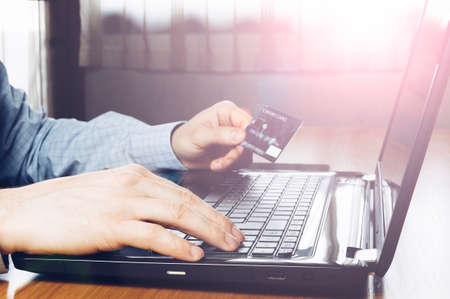 Man holding credit card and using keyboard laptop. Online payment (Intentional sun glare and lens flares)の写真素材