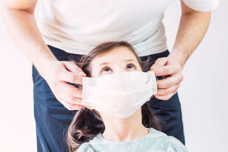 Dad Putting a Mask on his Daughter. Coronavirus Covid 19の写真素材
