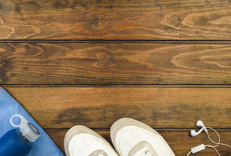 Fitness equipment top view with copy space. Water bottle, sport shoes and headphones on wooden background.の写真素材